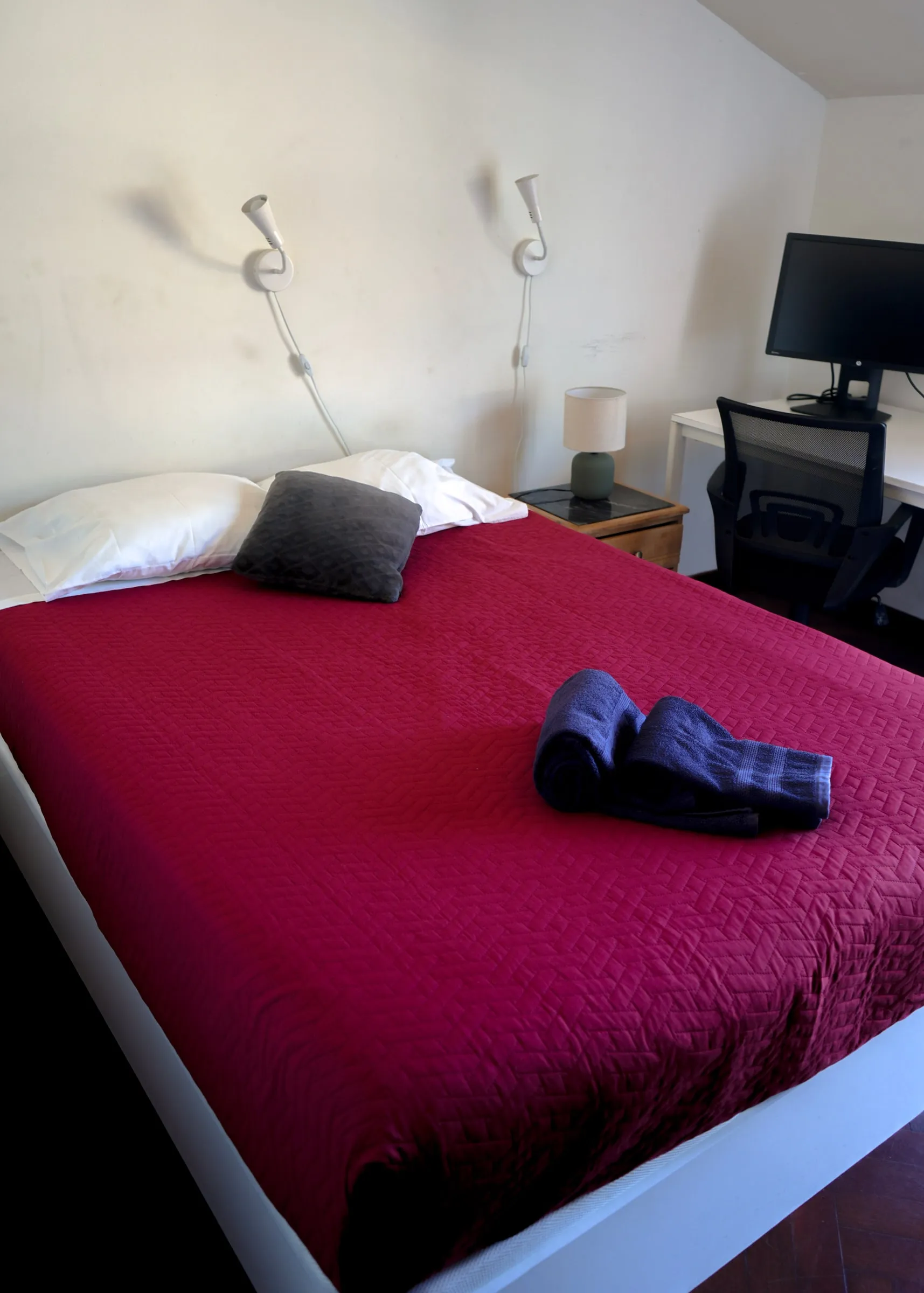 Bucatini double bed with a red cover beside the work desk